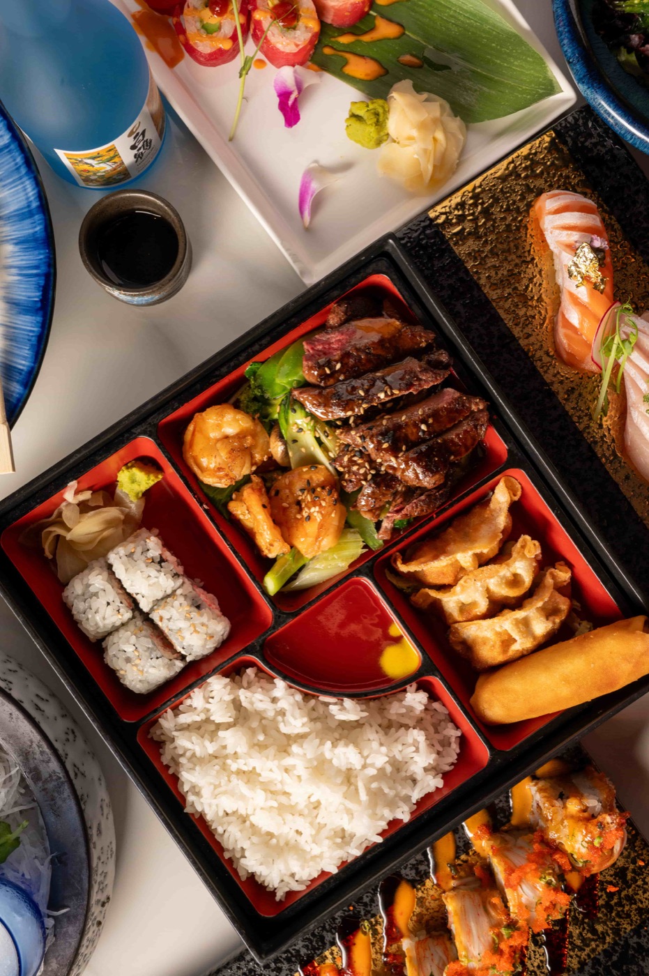 Sushi deluxe bento box with nigiri, California roll, gyoza, teriyaki beef and rice - East Moon Centennial CO