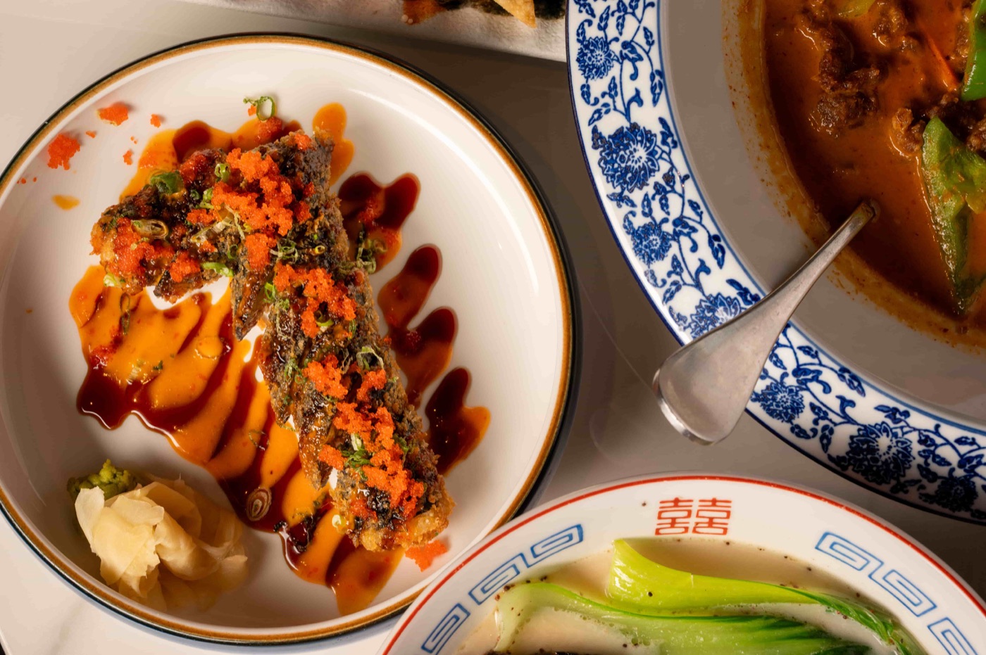 Deep-fried specialty roll topped with flying fish roe, scallion and eel sauce - East Moon Asian Bistro Centennial CO
