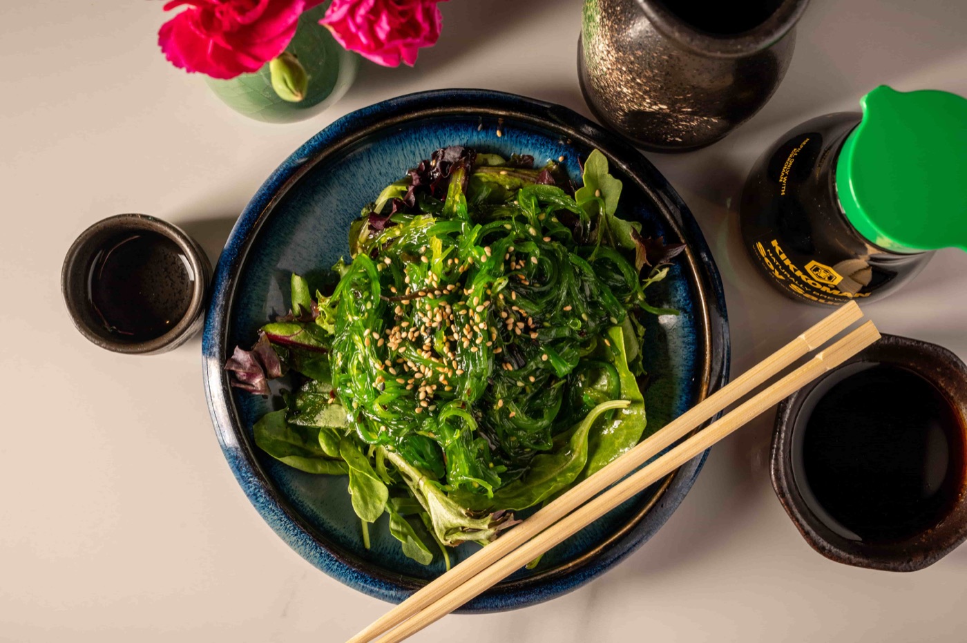 Overhead view of seaweed salad served with dipping sauce and chopsticks - East Moon Centennial CO