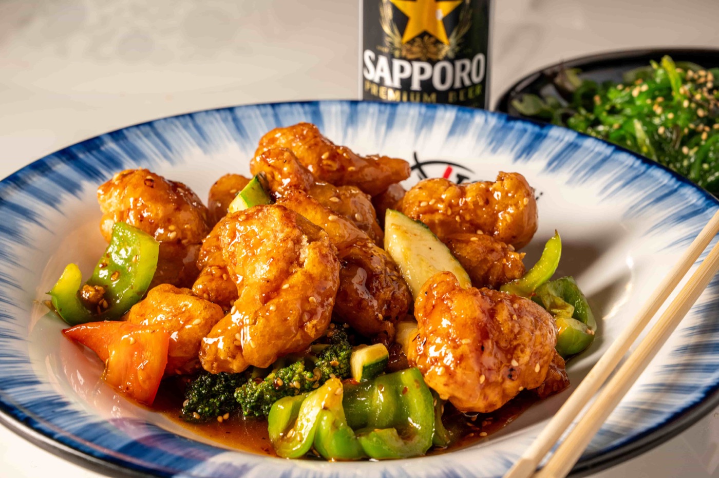 Sesame Chicken glazed in sweet sesame sauce with broccoli, bell pepper and zucchini - East Moon Asian Bistro Centennial CO